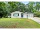 Charming single-story home with a white brick exterior, blue door, and a well-manicured front lawn surrounded by mature trees at 1694 Pheasant Dr, Atlanta, GA 30238