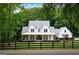 Beautiful white farmhouse with a covered porch, set on a spacious lot with mature trees and a black fence at 2101 Thomas Rd, Canton, GA 30115
