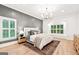 A spacious bedroom features a chandelier, hardwood floors, and large windows with decorative white molding at 3088 Hidden Falls Dr, Buford, GA 30519