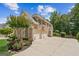 Three-car garage of a brick home, surrounded by lush greenery and mature trees on a sunny day at 3088 Hidden Falls Dr, Buford, GA 30519