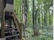 Backyard with wooden staircase leading up to a covered deck surrounded by a lush green forest and fenced yard at 372 Nalley Dr, Stone Mountain, GA 30087