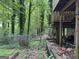 Backyard with lush greenery, mature trees, and a partial view of the house with a deck and staircase at 372 Nalley Dr, Stone Mountain, GA 30087
