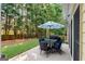 Outdoor patio with dining set, umbrella, grill, and string lights in a tree lined back yard at 2740 Greymont Ct, Cumming, GA 30041