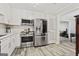 This kitchen boasts stainless steel appliances, white cabinetry, and stylish wood-look floors at 4113 Ashford Green Dr, Duluth, GA 30096
