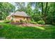 Manicured lawn shows landscaping, a brick home, and a lovely green area behind the home at 3030 Spalding Dr, Sandy Springs, GA 30350