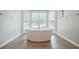 Elegant soaking tub in a neutral bathroom with a bay window offering natural light and serene views at 3030 Spalding Dr, Sandy Springs, GA 30350