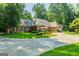 Sprawling single story brick home with mature trees, luscious lawn, and a horseshoe driveway at 3030 Spalding Dr, Sandy Springs, GA 30350