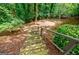 Backyard wooden stairs lead down to a playground area with a swing set and leafy trees at 3030 Spalding Dr, Sandy Springs, GA 30350