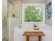 Bright bathroom features a glass shower, soaking tub, and wooded backyard views at 210 Hunters Vw, Roswell, GA 30075