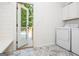Bright laundry room with white cabinets, washer, dryer, and an open door to the outdoor deck at 210 Hunters Vw, Roswell, GA 30075
