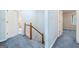 Hallway with blue carpet leading to different rooms, featuring a staircase with wooden handrail at 3 Maplelake Dr, Acworth, GA 30101