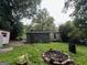 View of home from backyard, showing the roof, siding, shed, and a stone fire pit at 766 Warren Dr, Riverdale, GA 30296