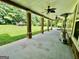 Covered patio with ceiling fans, stone-wrapped columns, and a spacious green backyard with playground at 345 Peaceful Way, Fayetteville, GA 30214