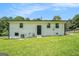 Exterior view of back of white home with grassy lawn and black door and trim details under bright blue sky at 4020 Ester Sw Dr, Atlanta, GA 30331
