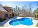 Expansive backyard with a pool, stone patio, and lush greenery, ideal for outdoor living and entertaining at 297 Collegiate Dr, Powder Springs, GA 30127
