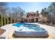 Backyard pool and hot tub with stone patio in a luxurious, two-story brick home surrounded by trees at 297 Collegiate Dr, Powder Springs, GA 30127