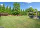 Beautifully landscaped backyard with lush green lawn, mature trees, and a covered patio area at 3015 Arbor Song Ct, Cumming, GA 30041