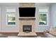 Close-up of a stone fireplace with a wooden mantel, flanked by windows and built-in shelving at 3015 Arbor Song Ct, Cumming, GA 30041