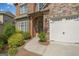 Inviting entrance with a stone archway, a white garage door, and a beautifully landscaped yard at 3015 Arbor Song Ct, Cumming, GA 30041