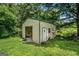 Backyard shed with roll-up door and surrounded by lush greenery on a sunny day at 2067 Skyhawk Ln, Acworth, GA 30102