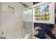 Bathroom featuring a walk-in shower with glass doors, white tile, and a window at 345 Adelle Se St, Atlanta, GA 30315