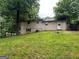 View of the house and grassy backyard with trees providing shade and an entry door at the rear of the house at 718 Hardy Way, Hiram, GA 30141