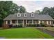 Charming brick home featuring a covered porch with dormer windows and lush landscaping at 79 The Farm Rd, Mcdonough, GA 30252