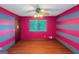 Bedroom with hardwood floor, pink wall with gray stripes, window, and a ceiling fan at 959 Sweet Briar Se Trl, Conyers, GA 30094