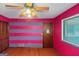 Bedroom with hardwood floor, pink wall with gray stripes, window, and ceiling fan at 959 Sweet Briar Se Trl, Conyers, GA 30094