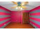 Bedroom with hardwood floor, pink wall with gray stripes, a window, and ceiling fan at 959 Sweet Briar Se Trl, Conyers, GA 30094