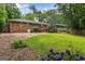 Spacious backyard with a brick home, deck, lush green lawn, and vibrant purple flowers at 2163 Medfield Ne Trl, Chamblee, GA 30345