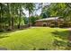 Large backyard offers a spacious lawn, mature trees, wooden fence, and a brick house with a deck for entertaining at 2163 Medfield Ne Trl, Chamblee, GA 30345