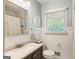 Well-lit bathroom featuring a vanity, toilet, and shower with classic white wainscoting and blue-grey walls at 2163 Medfield Ne Trl, Chamblee, GA 30345