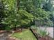 Backyard with lush greenery and a glimpse of a tennis court at 149 Crown Oaks Dr, Stockbridge, GA 30281
