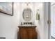 Cozy half bathroom with a wood vanity, oval mirror, and decorative accents at 149 Crown Oaks Dr, Stockbridge, GA 30281