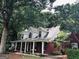 Beautiful brick home with a large front porch, complete with swing, surrounded by lush greenery at 149 Crown Oaks Dr, Stockbridge, GA 30281