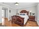 Spacious bedroom featuring a decorative wooden bed frame, two bedside tables with lamps, and hardwood floors at 420 Heritage Park Nw Trce # 22, Kennesaw, GA 30144