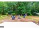 Backyard fire pit area with Adirondack chairs in a wooded setting; features red outbuilding at 264 Line Creek Cir, Sharpsburg, GA 30277