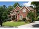 Lovely brick home with lush landscaping, mature trees, and a welcoming front porch at 200 Long Needle Ct, Sugar Hill, GA 30518
