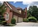 Side view of a brick home with an attached two car garage and well maintained landscaping at 200 Long Needle Ct, Sugar Hill, GA 30518