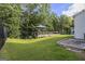 A lush backyard featuring a wooden deck, patio, green lawn, and a black iron fence with plenty of trees at 129 Academy Ln, Canton, GA 30114