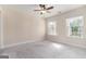 An empty carpeted bedroom with neutral walls featuring bright windows and a ceiling fan with lighting at 129 Academy Ln, Canton, GA 30114