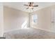 An empty carpeted bedroom with neutral walls featuring bright windows and a ceiling fan with lighting at 129 Academy Ln, Canton, GA 30114