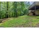 Large backyard with lush green grass, mature trees, and deck with stairs at 5341 Terrytown Ln, Lithonia, GA 30038