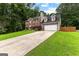 Brick two-story home with a long driveway and attached two-car garage nestled in a wooded area at 435 Hampton Grn, Peachtree City, GA 30269