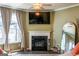 Inviting living room featuring a cozy fireplace, TV, and ample natural light from the adjacent windows at 13568 Scenic Pkwy, Covington, GA 30014