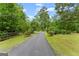 Scenic driveway leading to a hidden property, framed by lush trees, manicured lawn, and a wooden fence at 1572 Azalea Dr, Lawrenceville, GA 30043