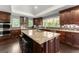 Kitchen featuring dark wood cabinets, stainless steel appliances, granite countertops, tile backsplash, and a kitchen island with seating at 1572 Azalea Dr, Lawrenceville, GA 30043