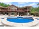 Backyard pool with a stone deck, showcasing a multi-level brick home with balconies and outdoor seating areas at 1572 Azalea Dr, Lawrenceville, GA 30043
