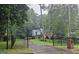 View of a two-story home featuring a combination of brick and siding, with wrought iron fencing, and tree lined driveway at 423 Orchards Walk, Stone Mountain, GA 30087